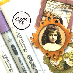 Close-up of Copic markers with a vintage-style card featuring a young girl's portrait.